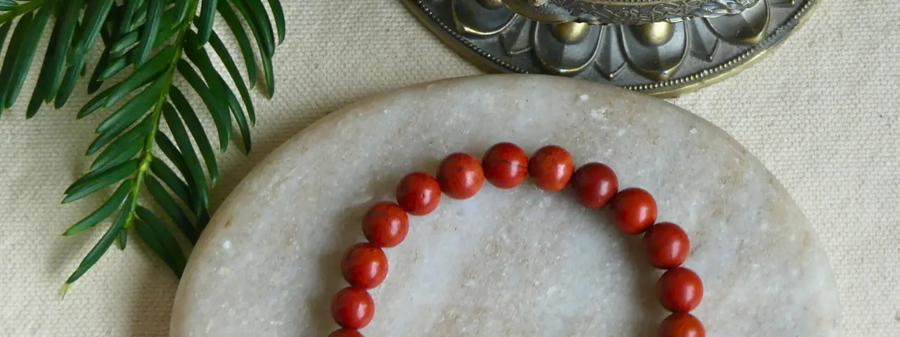 Un bracelet jaspe rouge posé sur un pierre