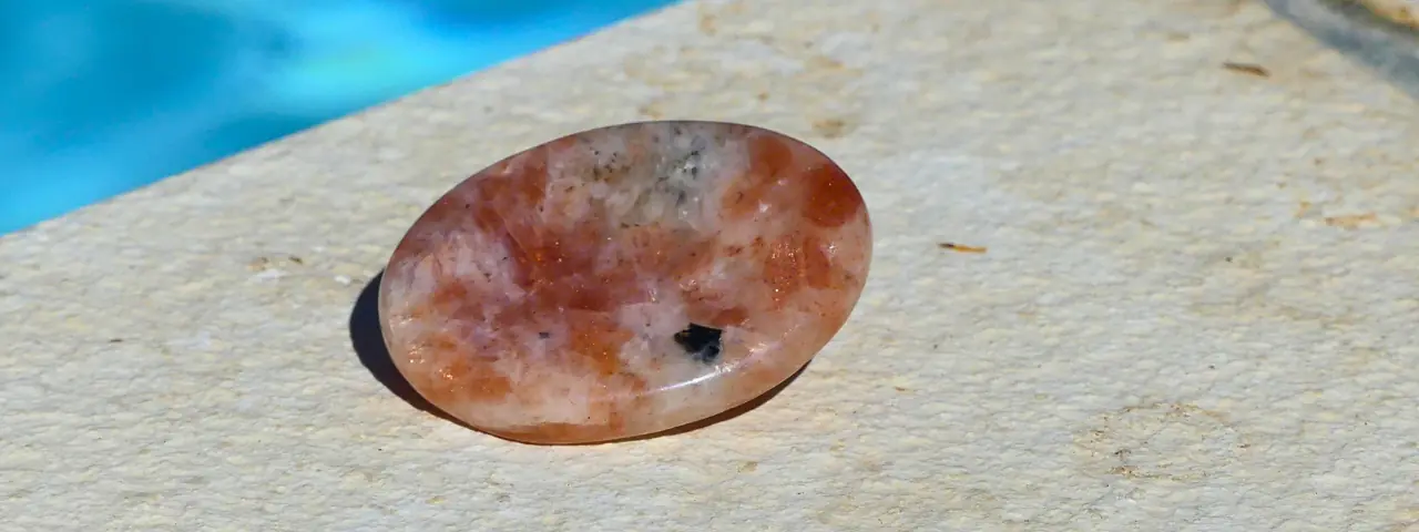 un galet anti stress en pierre de soleil posé au bord d'une piscine