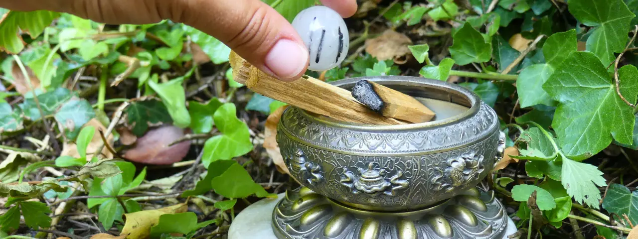 Palo santo allumé au côté d'un cristal de roche tourmaline