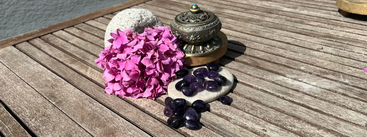 Pierre d'améthyste roulée posée sur une table au côté de fleurs