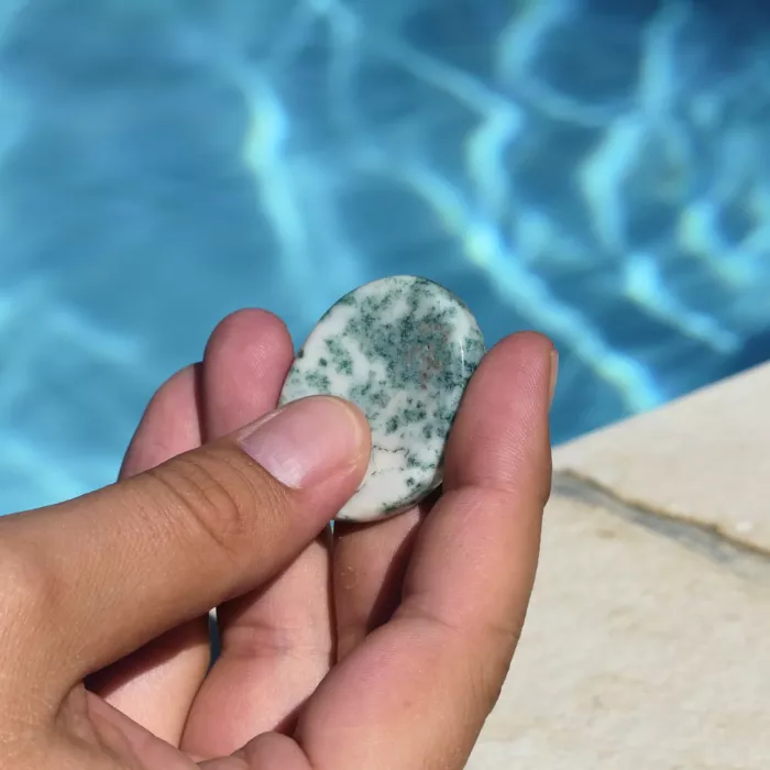 un galet anti stress agate arbre tenu par la main d'une jeune femme