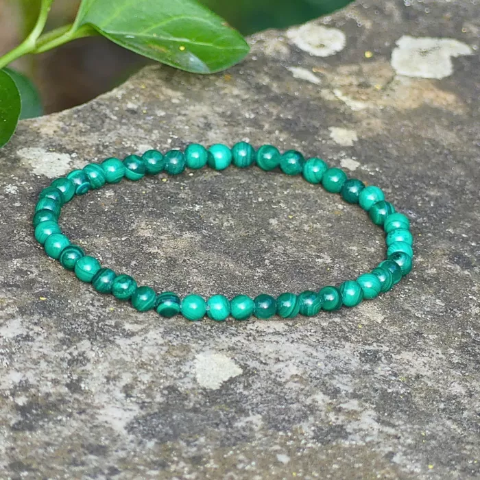 Un bracelet en malachite posé sur un rocher, mi ombre