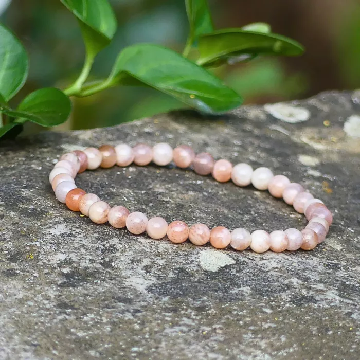 Un bracelet en pierre de soleil posé sur un rocher, mi ombre