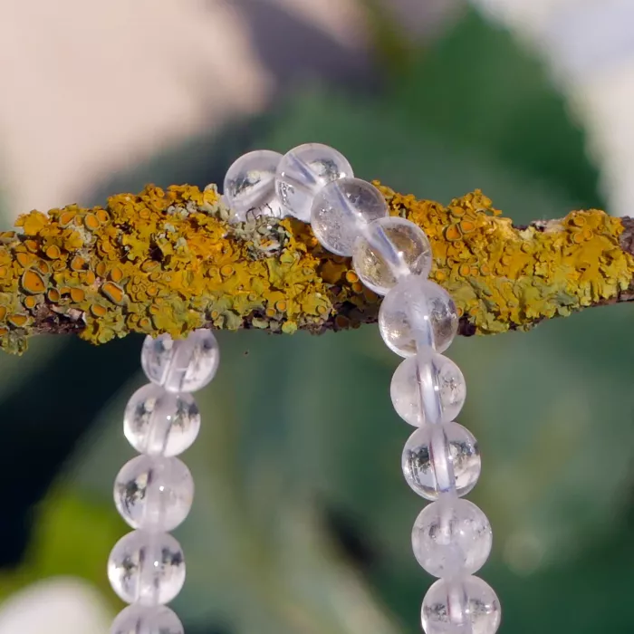 bracelet cristal de roche posé sur une branche en gros plan