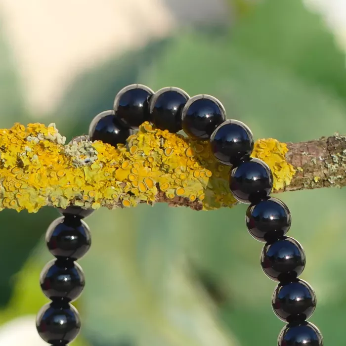 bracelet onyx sur une branche, à la verticale, en gros plan