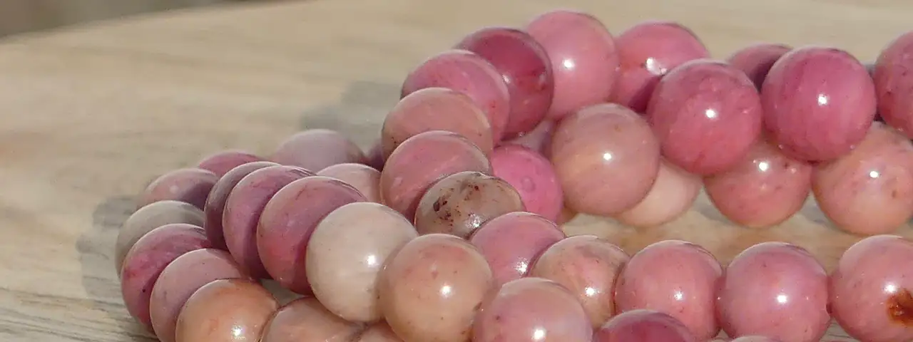 bracelet rhodonite sur une planche, dans un jardin en très gros plan