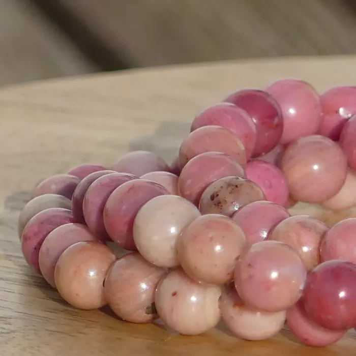 bracelet rhodonite sur une planche, dans un jardin en très gros plan