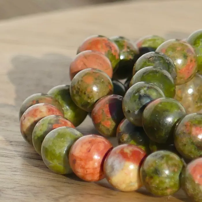 bracelet unakite posé sur une planche dans un jardin en très gros plan