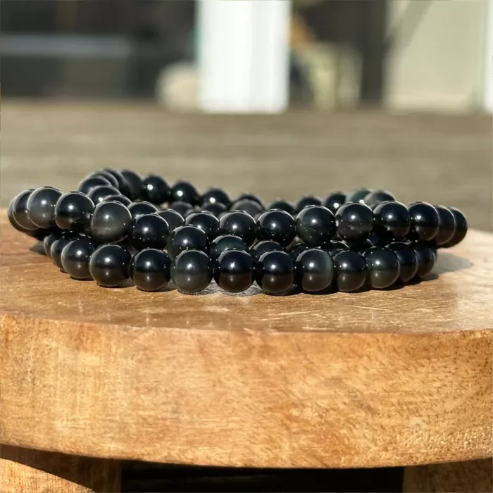 bracelet obsidienne dorée sur un socle en bois