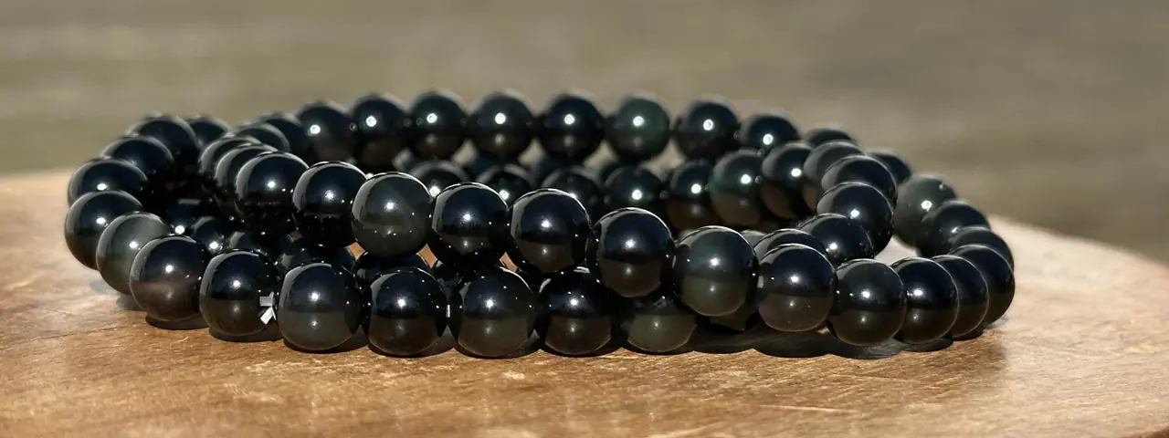 bracelet obsidienne dorée sur un socle en bois