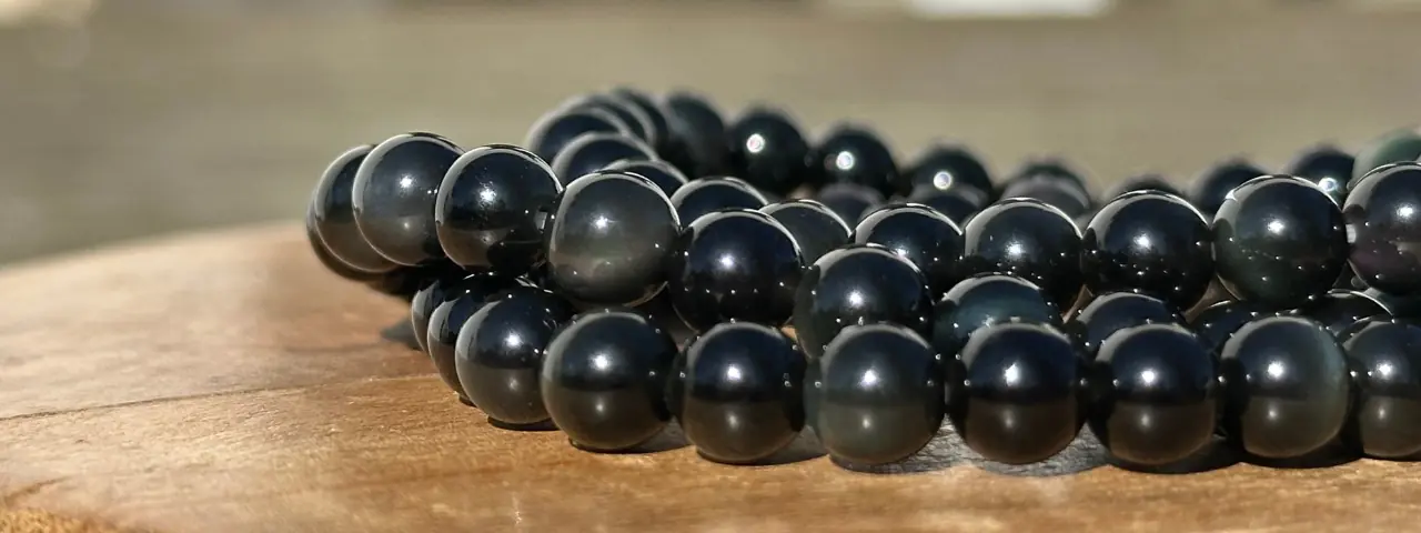 bracelet obsidienne dorée sur un socle en bois en gros plan