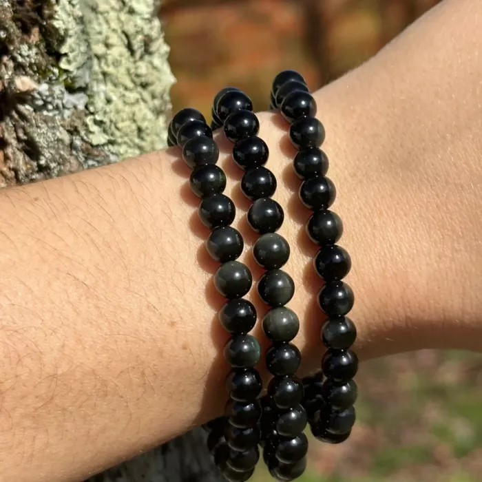 bracelet obsidienne dorée au poignet d'une jeune femme