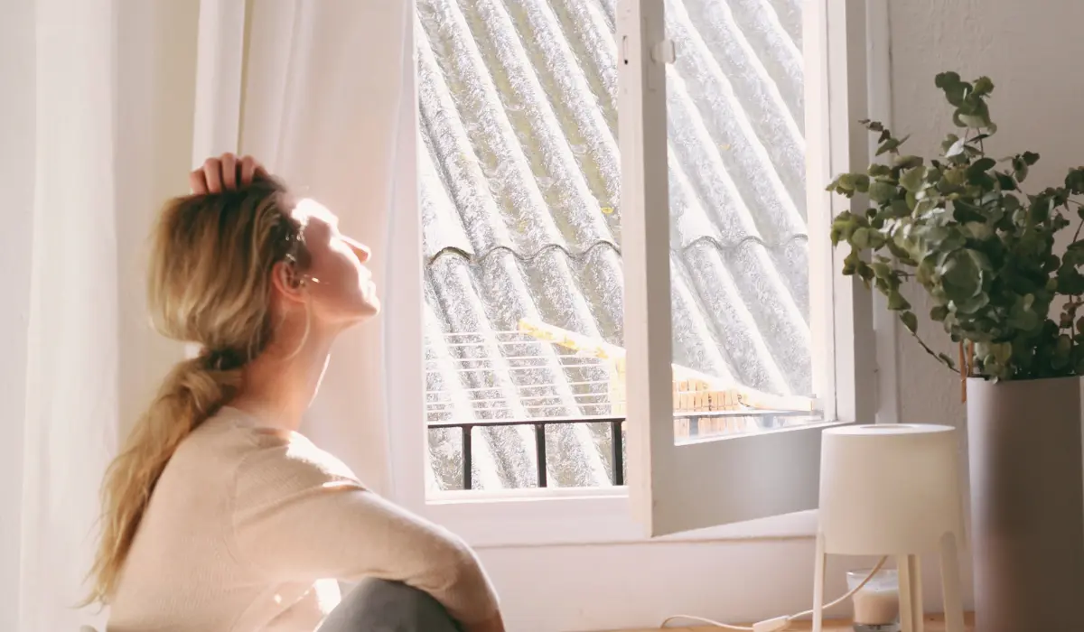Jeune femme se relaxant à la fenêtre de son appartement