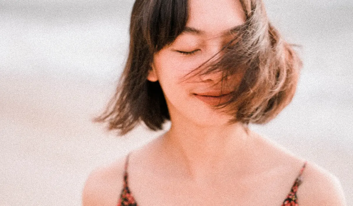 Jeune femme apaisée, cheveux légèrement dans le vent