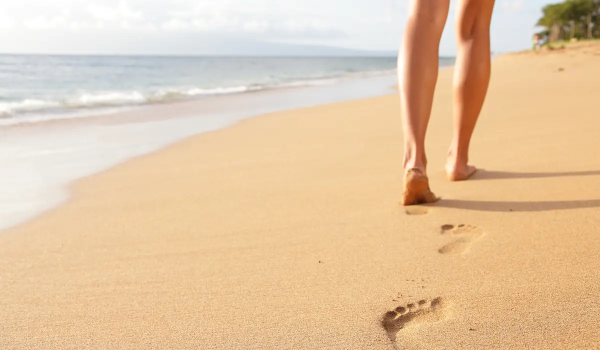 Jeune femme marchant lentement dans le sable