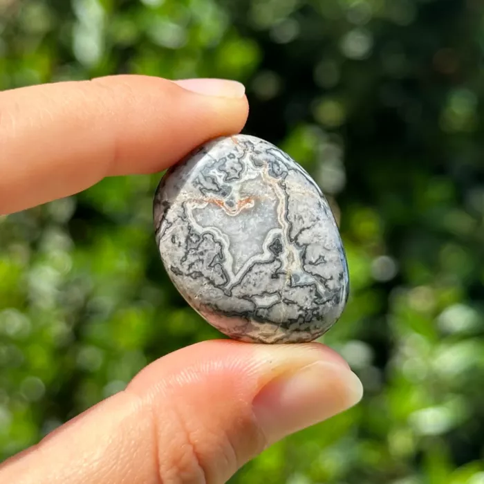 Agate crazy lace grise roulée entre les doigts d'une jeune femme
