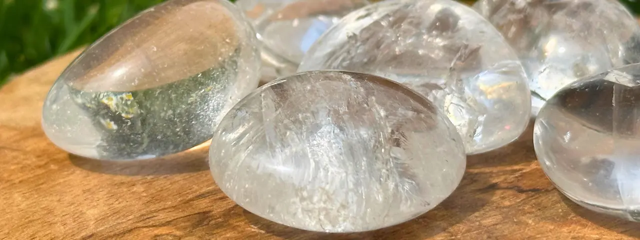 Du cristal de roche roulé posé sur une planche de bois