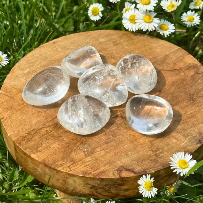 Du cristal de roche roulé posé sur une planche de bois
