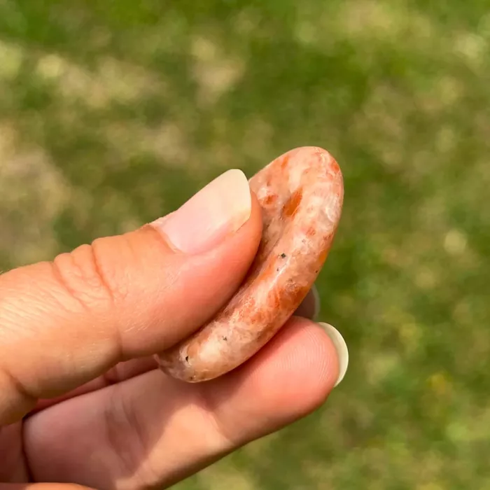 Galet anti-stress en pierre de soleil tenu dans la main
