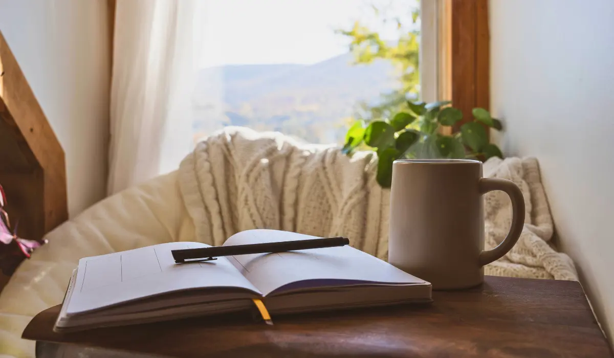 Un petit bureau sur lequel on a posé un carnet, un stylo et une tasse