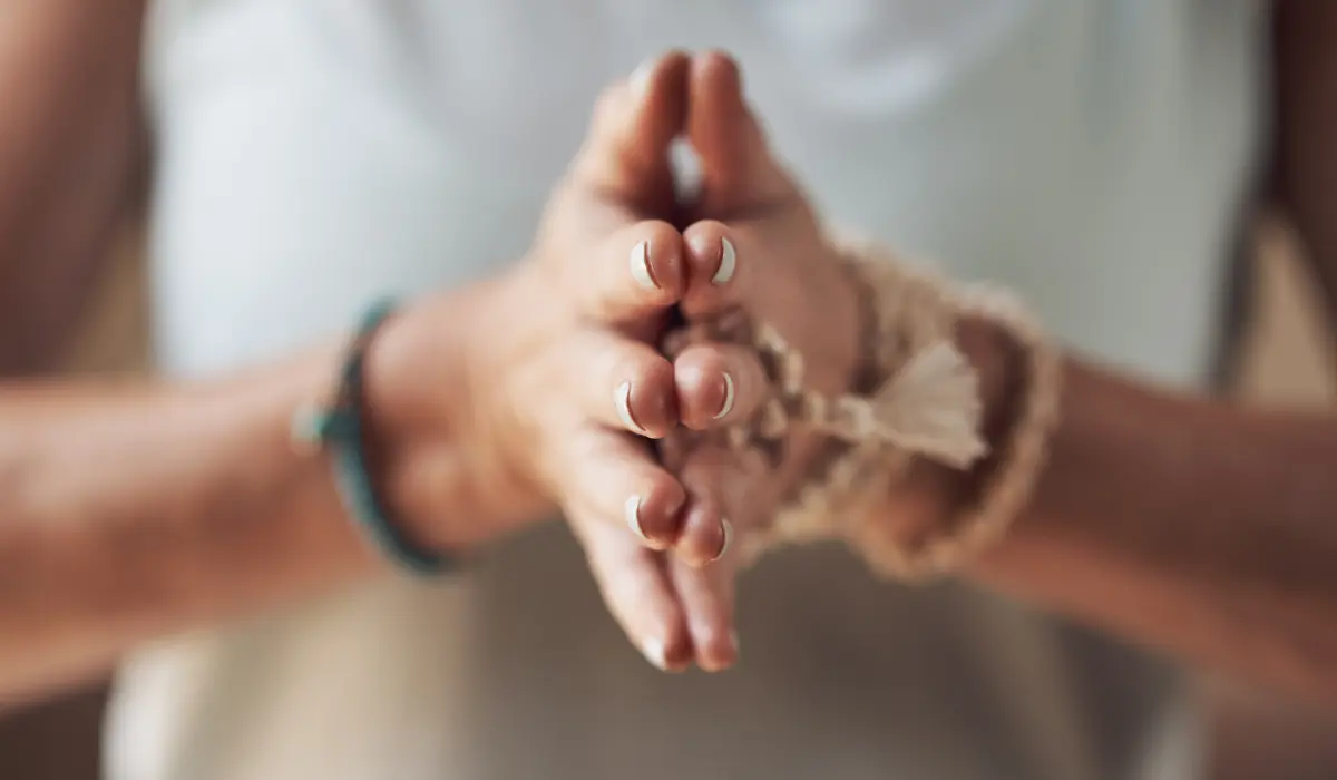 Un jeune femme joignant ses mains, comme pour effectuer une prière