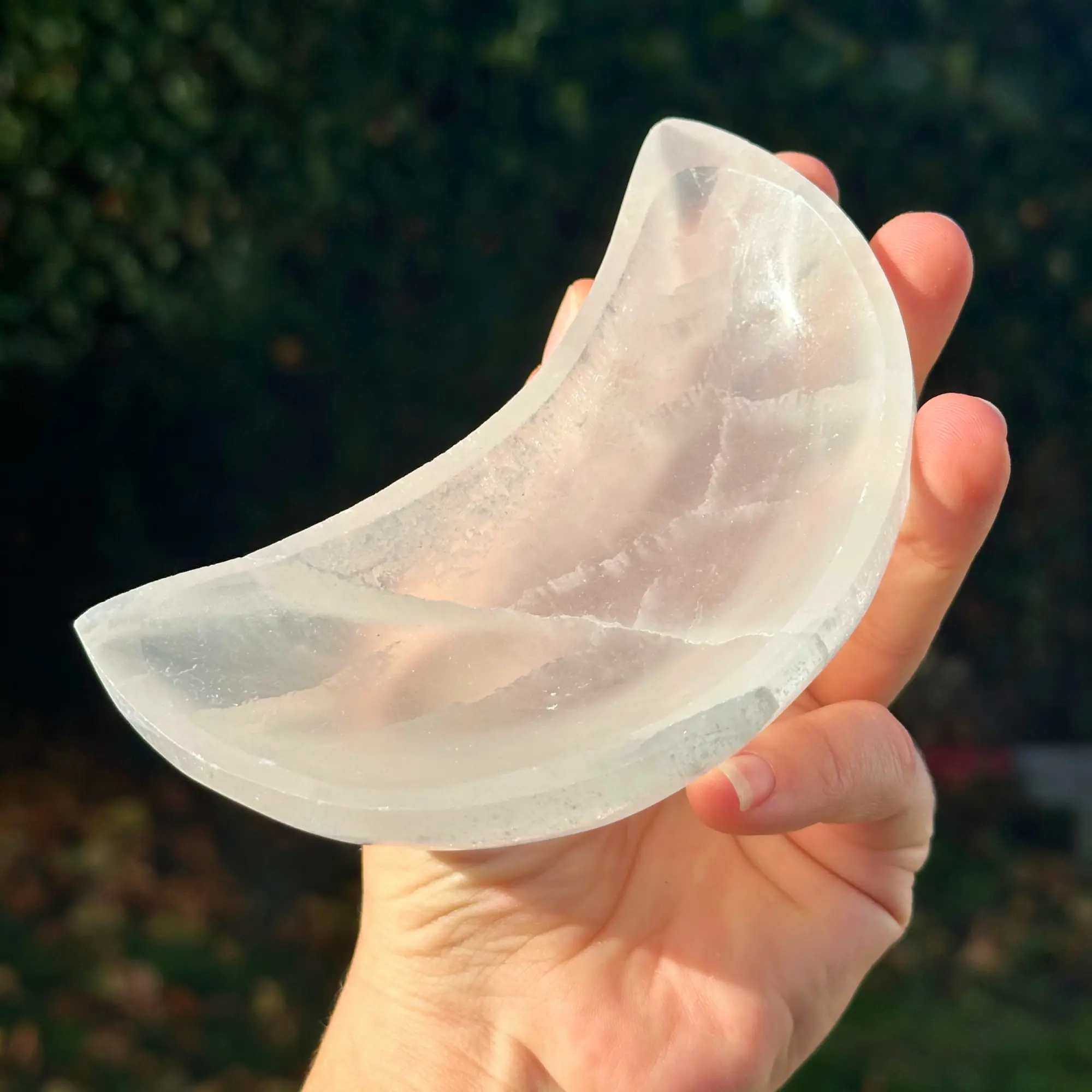 Bol sélénite lune tenu entre les doigts