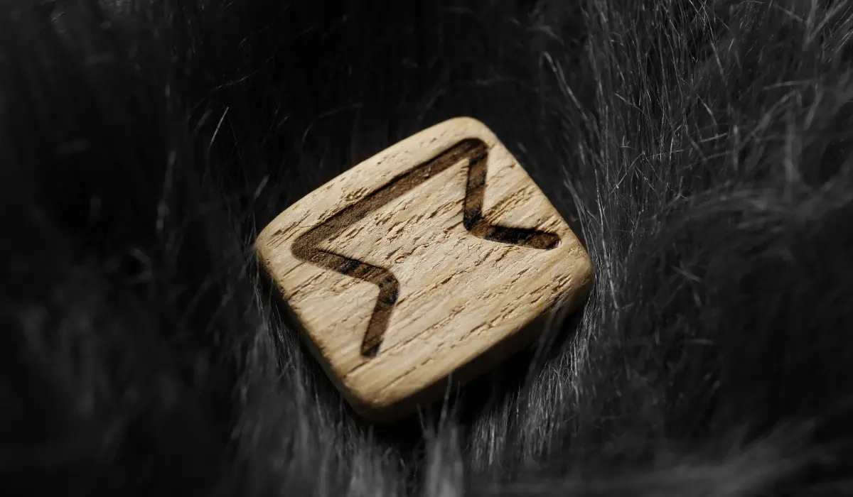 La rune Perthro en bois posée sur une fourrure noire