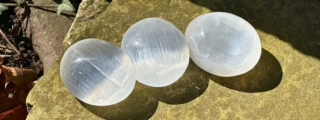 trois galets de sélénite posés sur un rocher