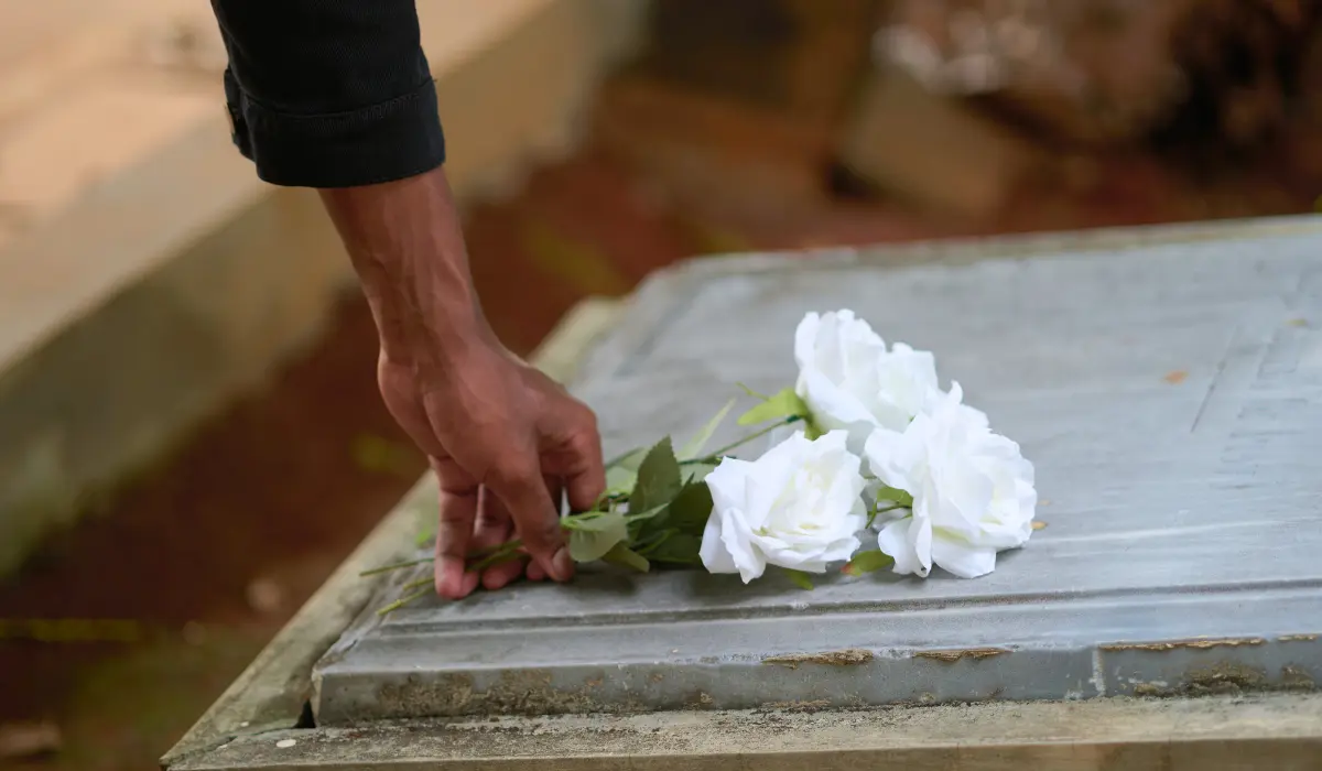Homme durant périodes de deuil laissant une fleur blanche sur une tombe