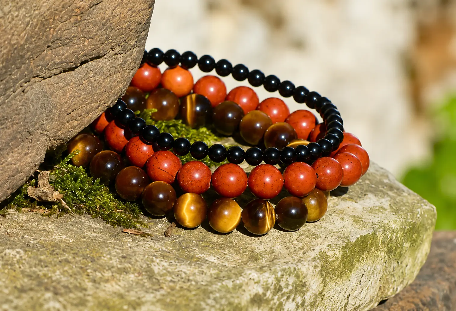 Plusieurs bijoux en pierre naturelle de couleur noir, marron posés sur une grosse pierre
